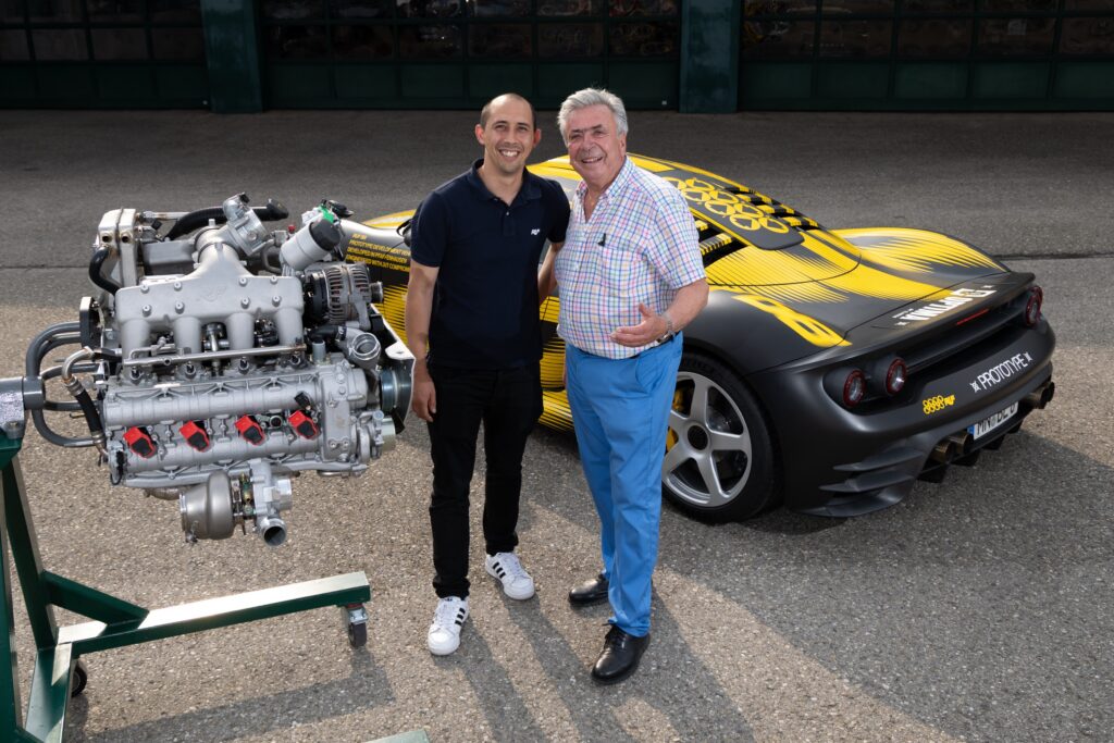 Two men stand next to an engine