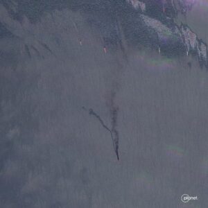 A Planet Labs satellite image shows black smoke billowing up from a ship in the Sea of Azov. Five other ships can be seen in the upper part of the image.