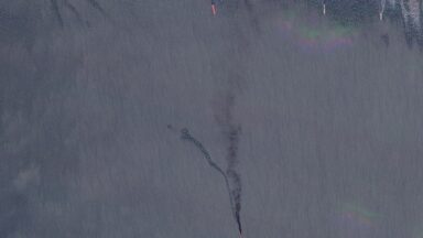 A Planet Labs satellite image shows black smoke billowing up from a ship in the Sea of Azov. Five other ships can be seen in the upper part of the image.