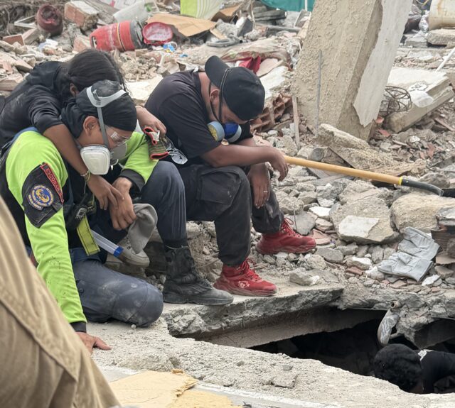 Mexican search and rescue workers from the volunteer group Los Topos sit near a sinkhole as they search for people among the rubble of collapsed buildings in Venezuela after two earthquakes struck on June 24.