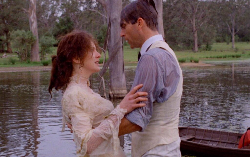 young man and woman embracing on a lakeshore with a boat tied up next to them