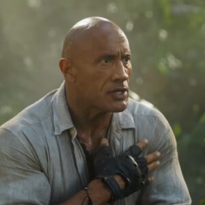 muscular bald man standing looking confused in a jungle