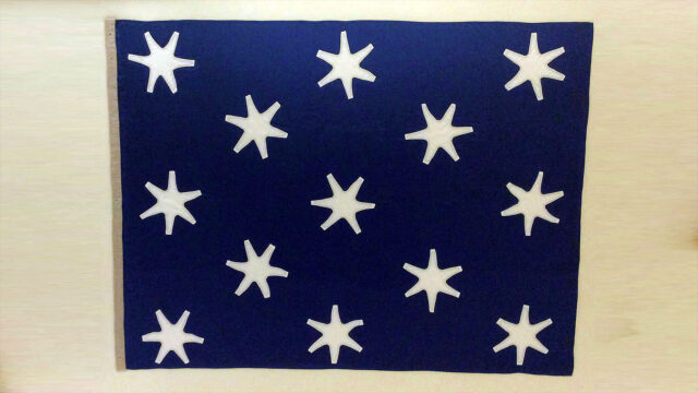 a rectangular flag with a deep blue background and 13 white stars.