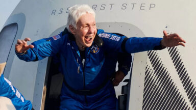 a woman with an excited expression exits a space capsule after it landed.