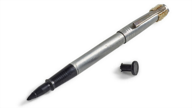A felt-tip black ink pen with its cap removed and a small broken-off cap from a circuit breaker switch