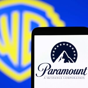 Paramount's logo displayed on a smartphone in front of a backdrop with the Warner Bros. logo