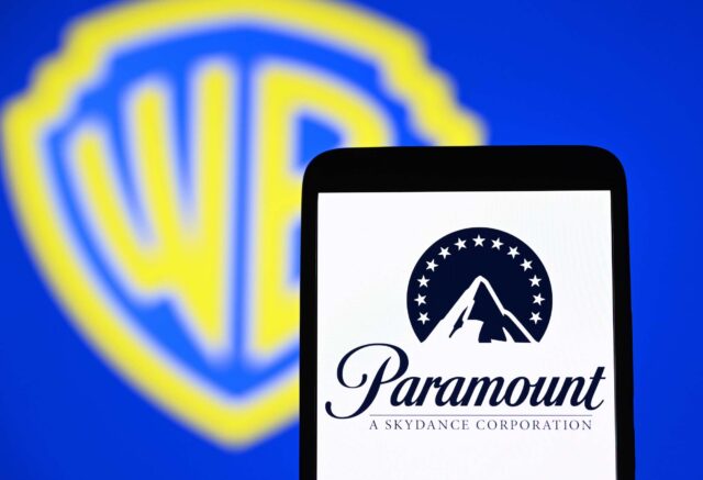 Paramount's logo displayed on a smartphone in front of a backdrop with the Warner Bros. logo