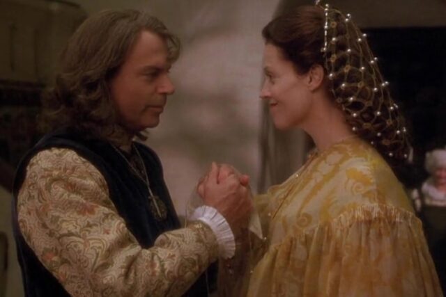 aristocratic man and woman in rich wedding garb; he is holding her hand and both are smiling