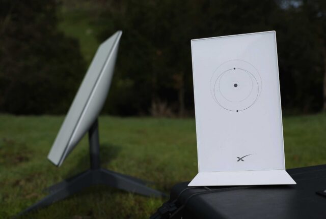 Picture of a Starlink satellite dish and router placed outside, on a lawn.