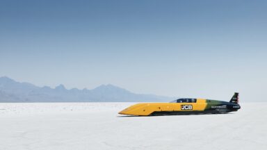 A yellow land speed record car on a salt flat