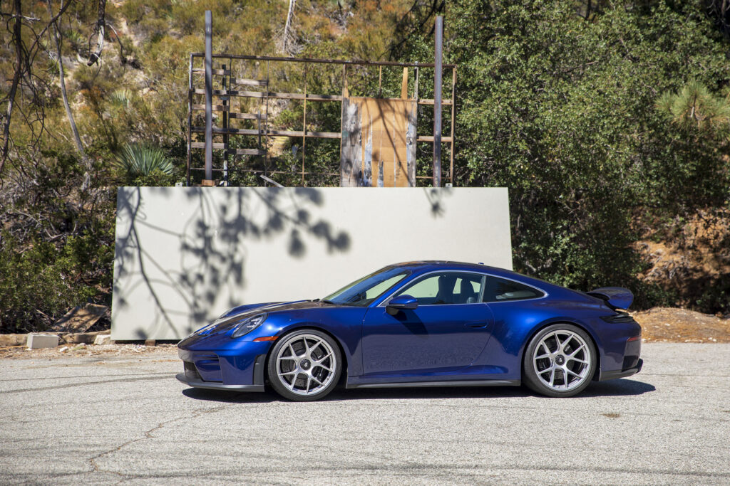 A blue Porsche 911 GT3 parked next to a blank billboard