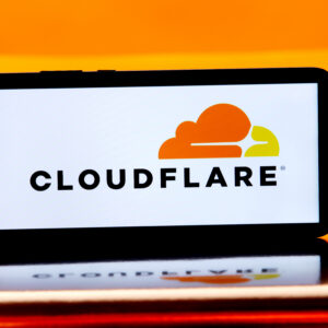 The Cloudflare company name and logo showing an orange and yellow cloud are displayed on the white screen of a smartphone sitting horizontally.