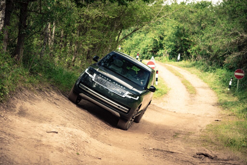 An electric Range Rover drives along a bank
