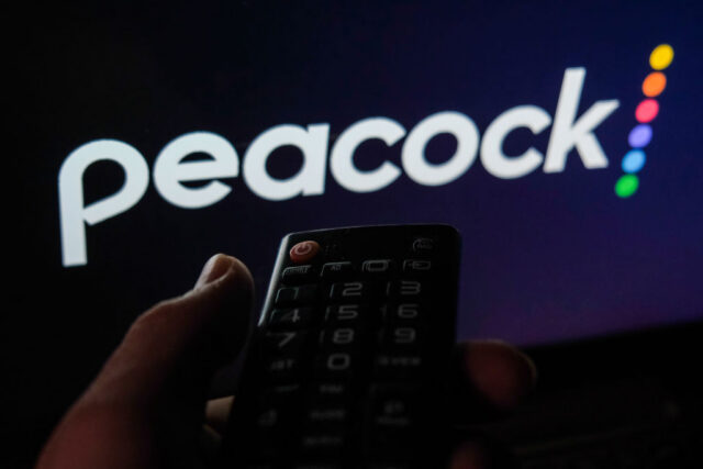 TV remote control is seen with Peacock logo displayed on a screen in this illustration photo taken in Krakow, Poland on February 6, 2022.