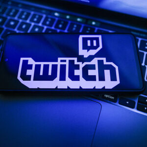 In this photo illustration, a Twitch logo is seen displayed on a smartphone on the top of a laptop.