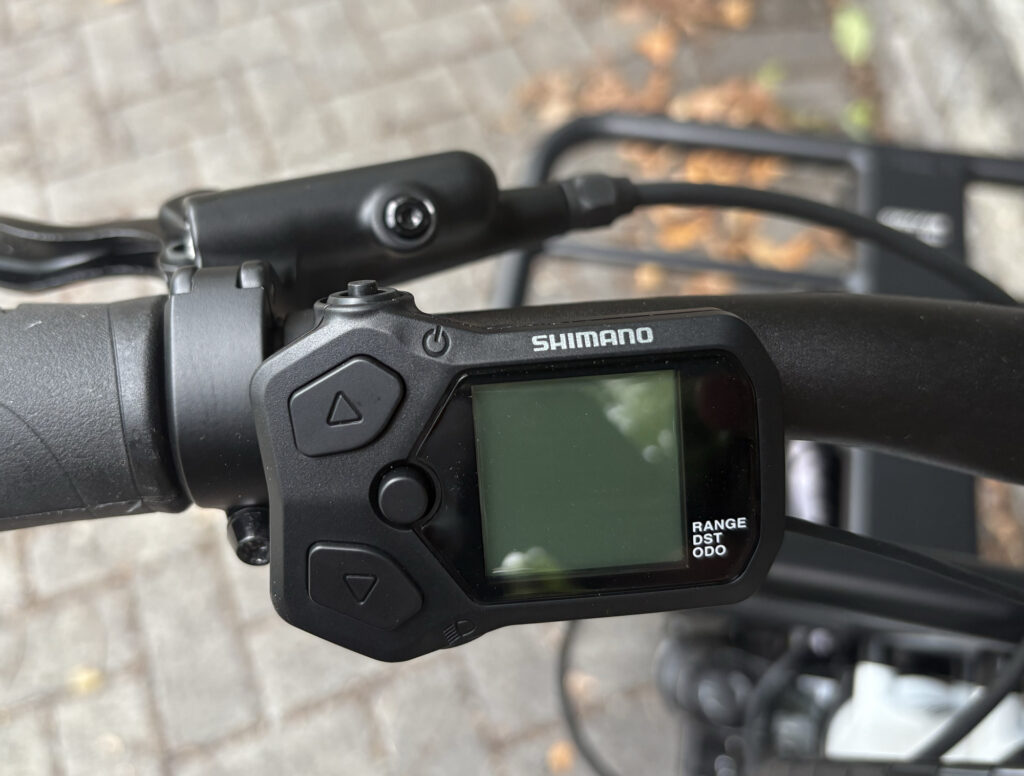 Image of part of a handlebar, showing a controller with a small screen and a few buttons.