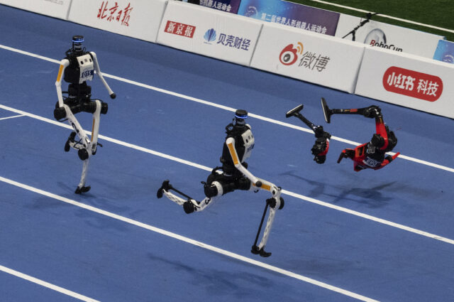 An Honor humanoid robot breaks into pieces as it runs next to two Tian Gong Ultras, center and left, in the second heat of the large robot category of the 100 meter at the 2nd World Robot Games at National Speed Skating Oval on August 25, 2026 in Beijing, China.