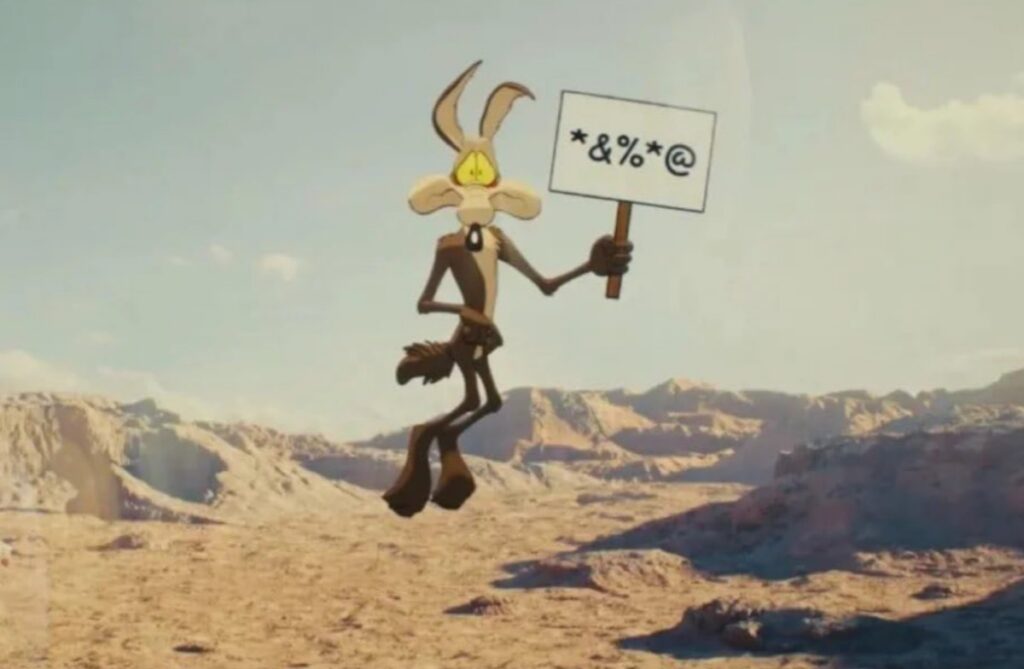 coyote in mid-air, about to fall, holding up a sign with symbols representing profanity