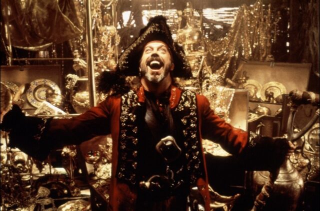 bearded pirate standing with arms outstretched and a joyful expression standing in front of a pile of gold treasure
