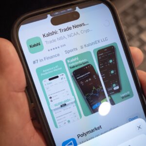 A person's hand holding a smartphone that displays the app store listing for Kalshi's prediction-market app.