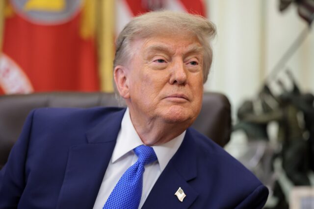 President Trump sitting at his desk during a press conference.