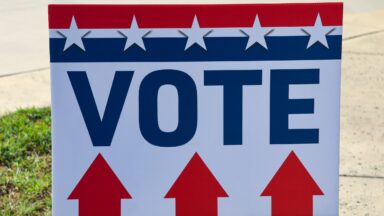 A “vote” sign with stars, stripes, and directional arrows to indicate where to go to vote or turn in ballots.
