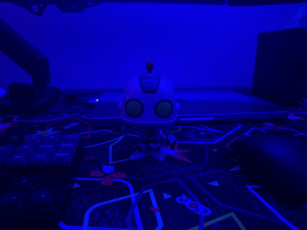 A robot figurine on a desk mat in front of a MacBook Pro