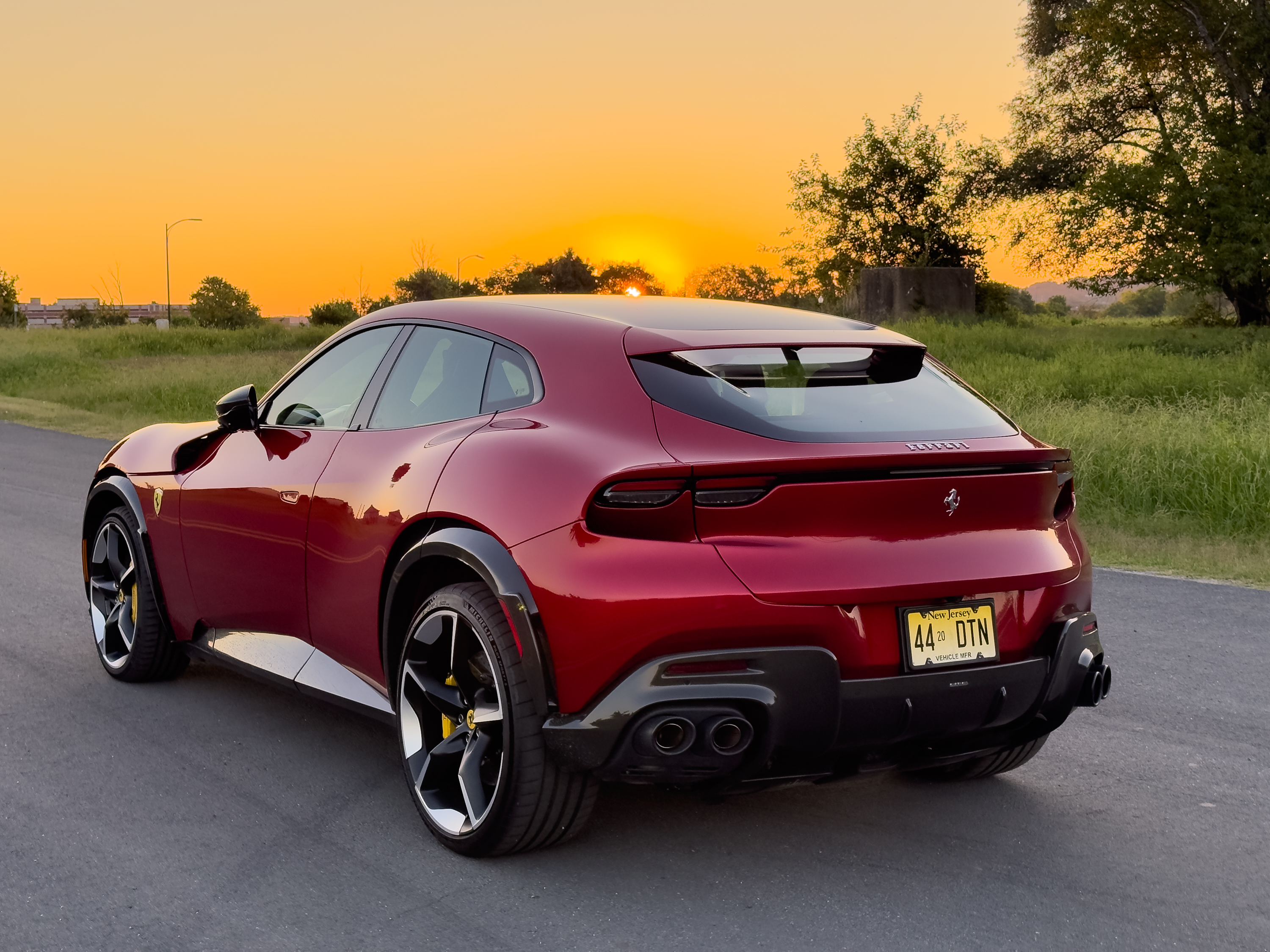 A red Ferrari Purosangue at dawn, seen from behind.