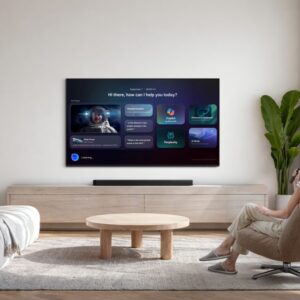 A woman sitting in a living room in front of a wall-mounted TV.