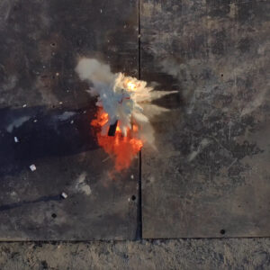 Fire retardant balls dropped by Anduril's Ghost-X drone explode on a fire in a test. The scene from above shows a cloud of fire retardant just spreading out with the blaze beneath it.