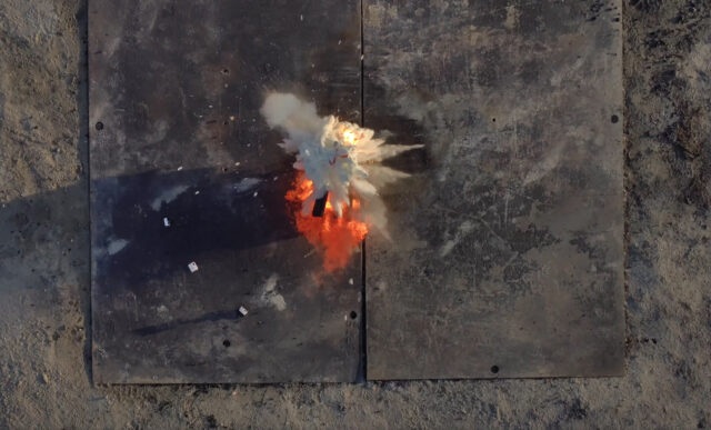 Fire retardant balls dropped by Anduril's Ghost-X drone explode on a fire in a test. The scene from above shows a cloud of fire retardant just spreading out with the blaze beneath it.