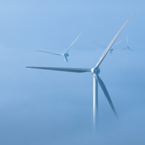 Wind turbine blades rising above some low level fog.