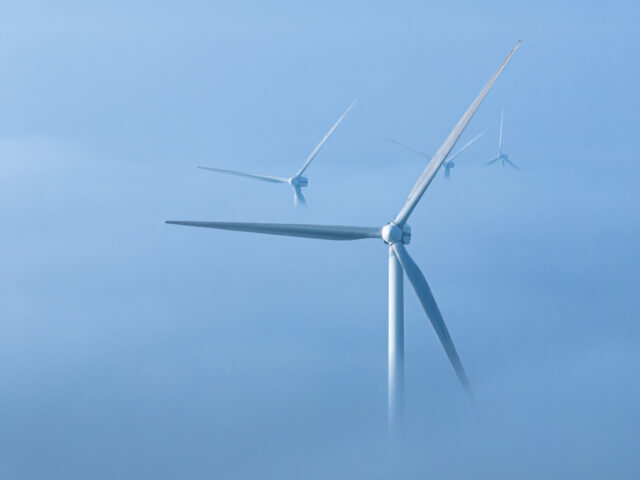 Wind turbine blades rising above some low level fog.