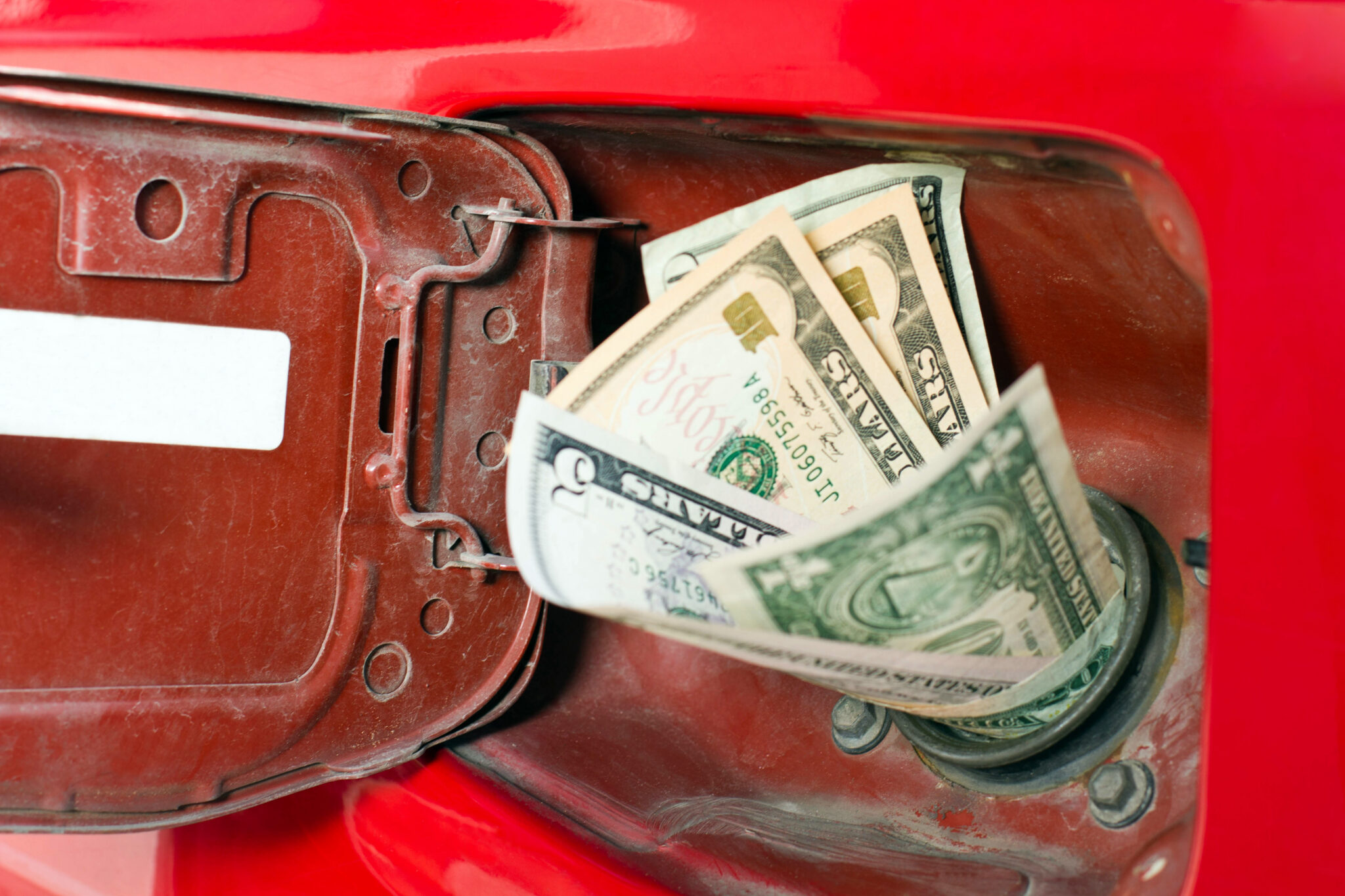 A car's gasoline filling port filled with dollar bills