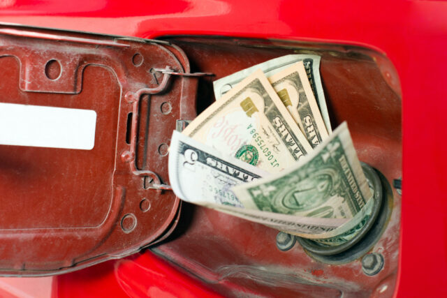 A car's gasoline filling port filled with dollar bills
