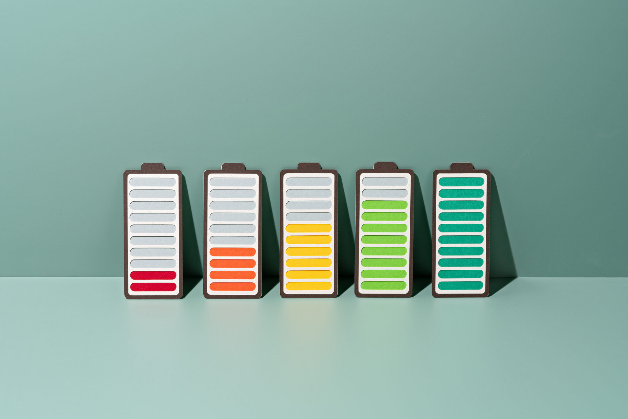 Paper Craft of a row of Rechargeable Batteries Gradually Charging to Full on a Green Background .