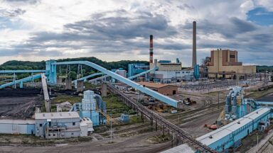 Image of a coal-fired power plant, showing lots of conveyor belts and a few smokestacks.