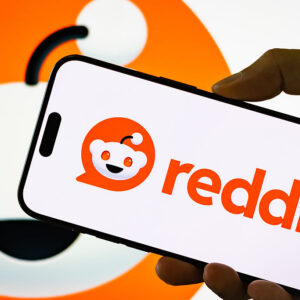 In this photo illustration, a person holds a smartphone displaying the logo of Reddit Inc.