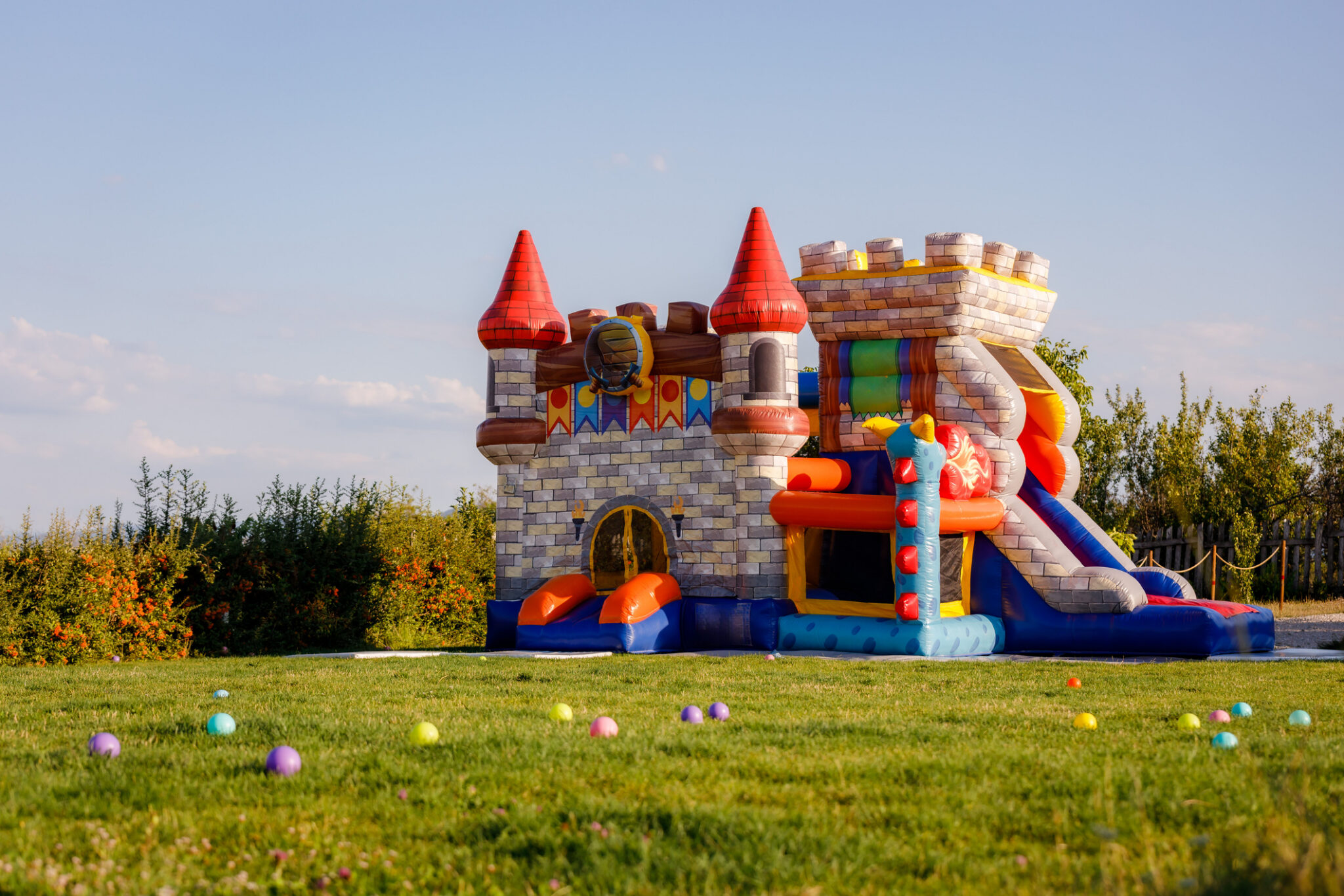 An inflatable castle bounce house sits in green field.