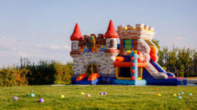 An inflatable castle bounce house sits in green field.