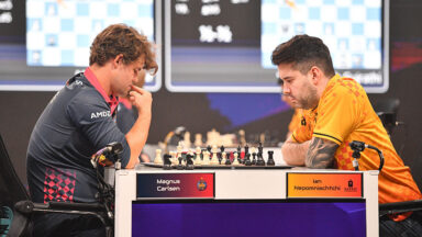 Two people playing chess as part of an organized competition.