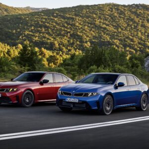 A red and a blue BMW 3 series drive along a road