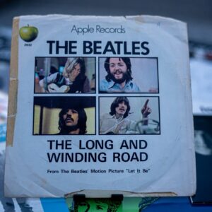 An original Apple Records single sleeve of "The Long and Winding Road," photographed among other Beatles records.
