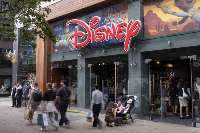 People walking on the sidewalk outside of a Disney store
