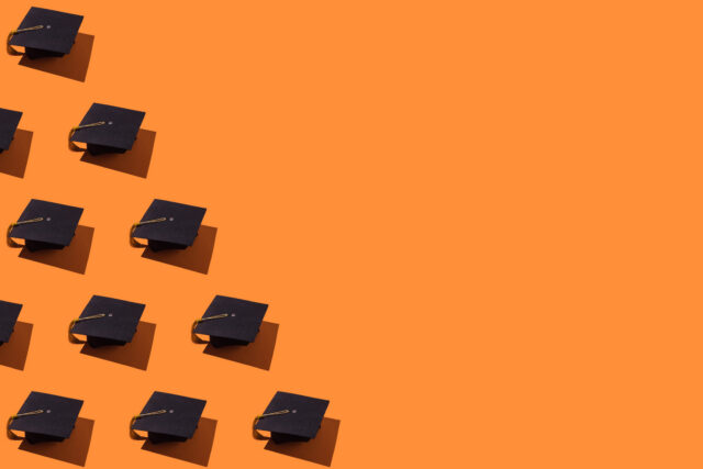 Pattern of black graduation caps with gold tassel with hard shadow, on the left side, on orange background