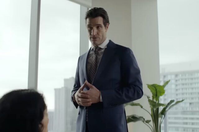 handsome dark haired man in an impeccable business suit standing in a corporate executive board room