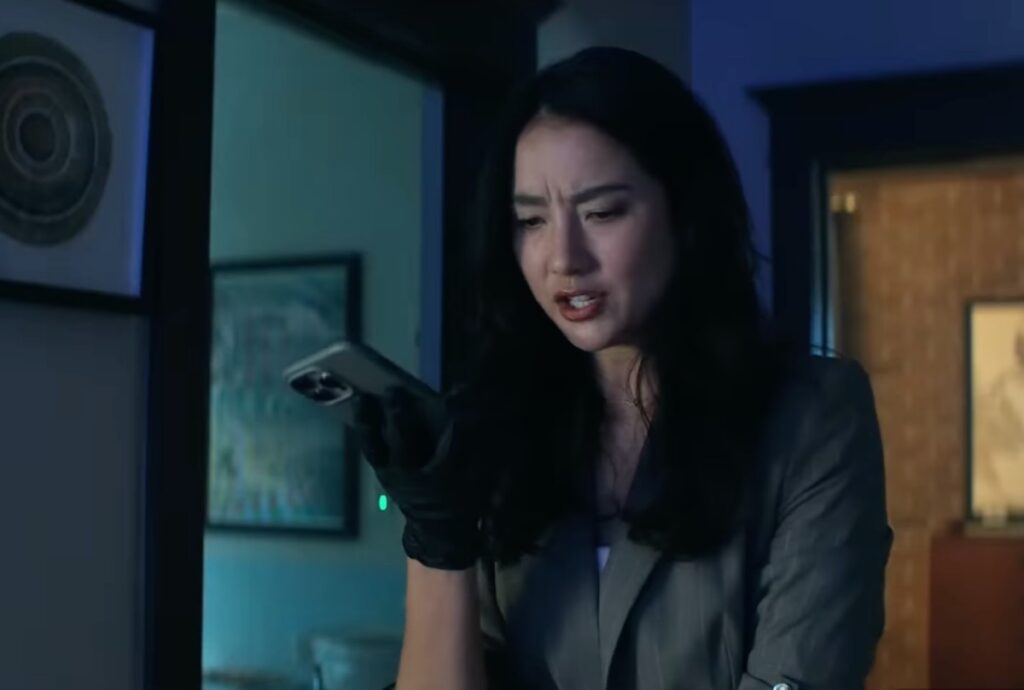 Asian woman with long back hair holding a cell phone with on hand looking concerned