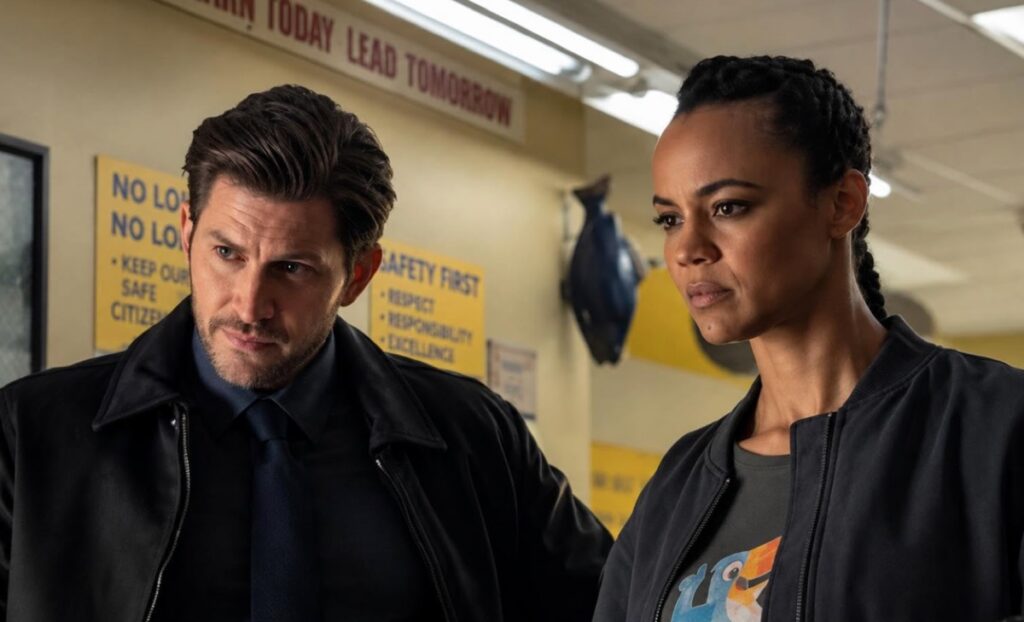 police detective with trimmed facial hair standing next to a determined black woman with her hair pulled tightly back