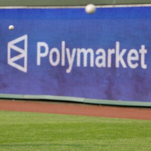 A Major League baseball player throws a ball during warmups, while a large sign advertising Polymarket is seen on the outfield wall.