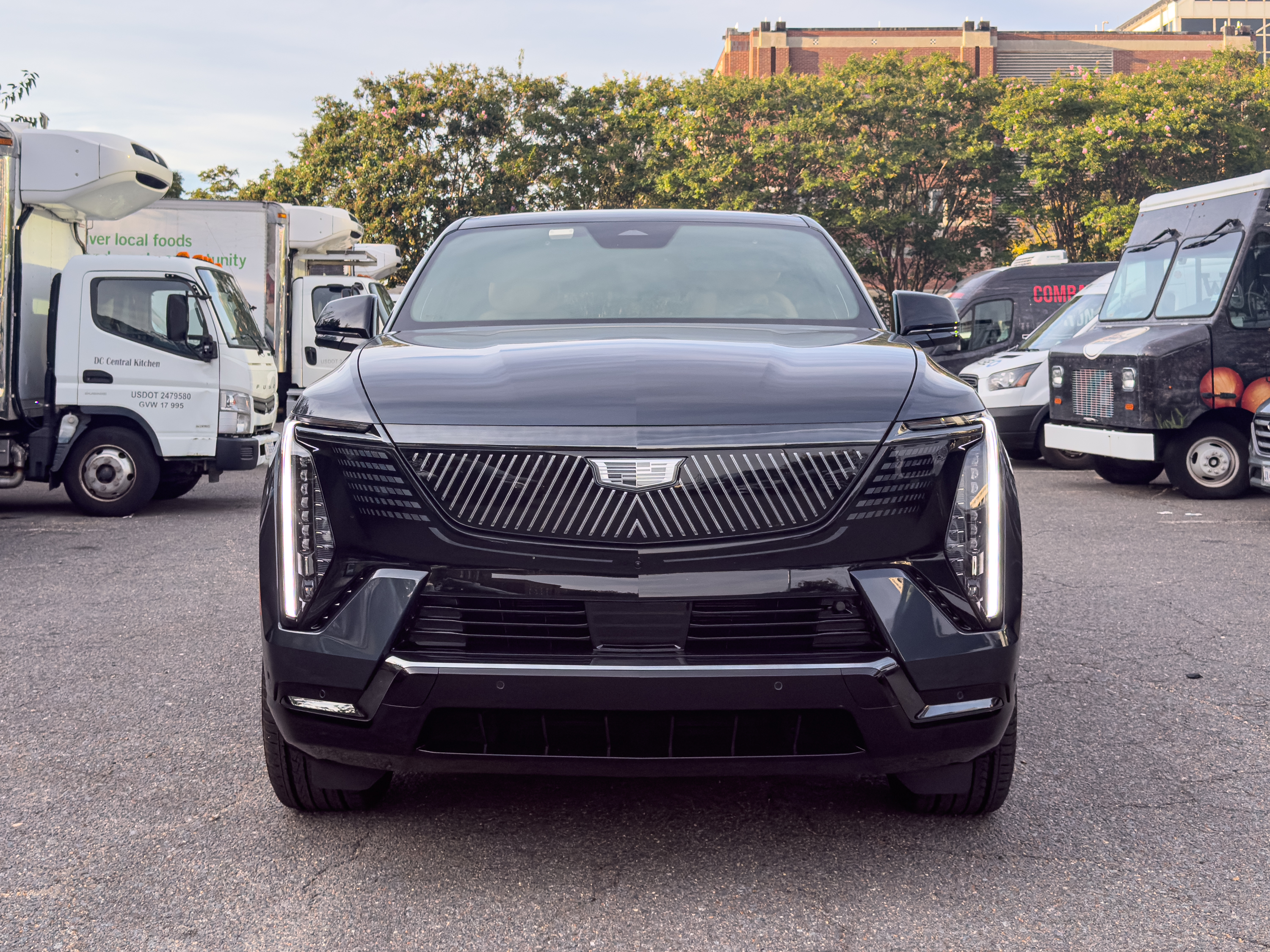A Cadillac Escalade IQ parked next to some box trucks